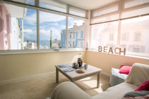 a living room with a couch and a table in front of a window at Ellesmere New Quay in New Quay