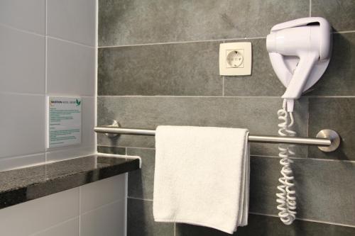 a phone hanging on a wall in a bathroom at Bastion Hotel Amsterdam Airport in Hoofddorp