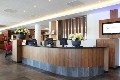 a hotel lobby with a reception counter with flowers at Bastion Hotel Amsterdam Airport in Hoofddorp