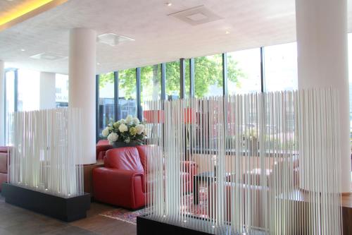 a lobby with a red chair and a vase of flowers at Bastion Hotel Amsterdam Airport in Hoofddorp