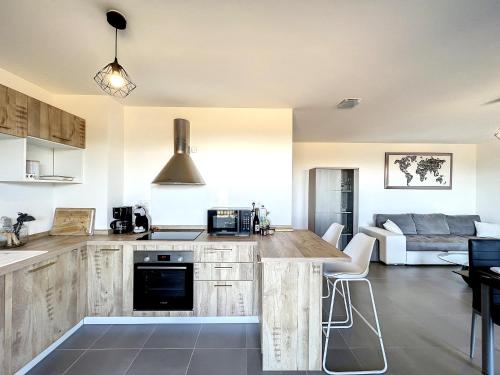 une cuisine avec des placards en bois et un salon dans l'établissement CALENZANA Appartement T3 avec vue mer !, à Calenzana