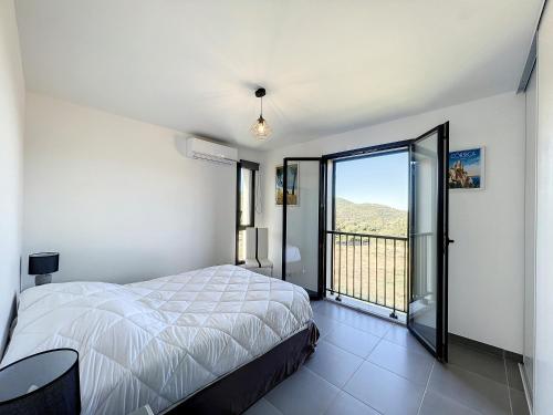 une chambre avec un lit et un balcon dans l'établissement CALENZANA Appartement T3 avec vue mer !, à Calenzana