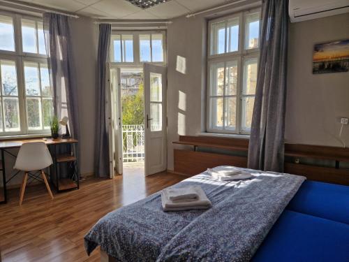 una camera con letto blu, finestre e scrivania di Lambo's Corner Varna - Guest Rooms a Varna
