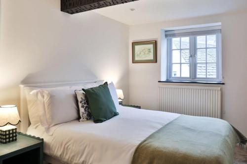 une chambre avec un lit blanc et une fenêtre dans l'établissement Alexis Cottage Tetbury Cotswolds, à Tetbury