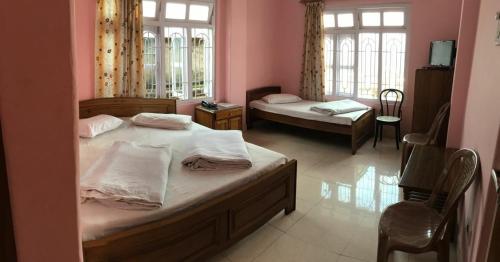 een slaapkamer met 2 bedden en 2 ramen bij Anjali Delux in Kalimpong