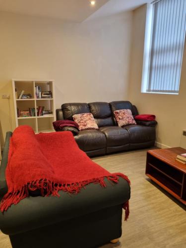 uma sala de estar com um sofá e um cobertor vermelho em Fabulous Home from Home - Central Long Eaton - Lovely Short-Stay Apartment - HIGH SPEED FIBRE OPTIC BROADBAND INTERNET - HIGH SPEED STREAMING POSSIBLE Suitable for working from home and students Very Spacious FREE PARKING nearby em Long Eaton