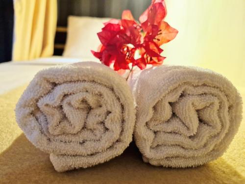 a pair of towels on a bed with a red flower at Karcof Container Hostel in Senggigi 