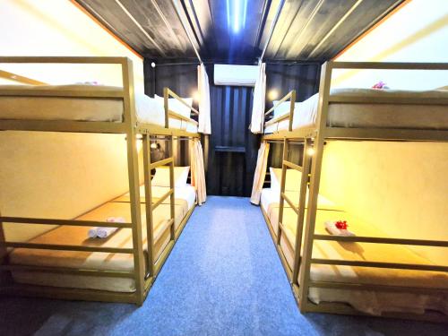 a room with three bunk beds in a house at Karcof Container Hostel in Senggigi 
