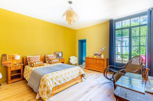- une chambre avec des murs jaunes, un lit et une fenêtre dans l'établissement La Dépendance - Piscine & Jardin dans Bordeaux, à Bordeaux