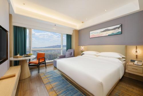 um quarto de hotel com uma grande cama branca e uma secretária em Urumqi Luolan Hotel em Ürümqi