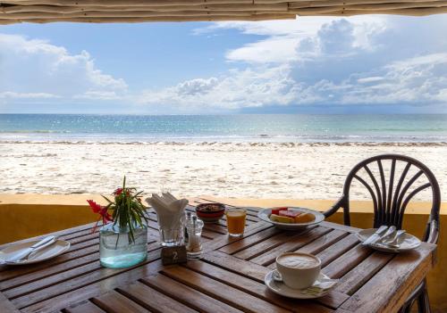 uma mesa de madeira com vista para a praia em Blue Marlin Beach Hotel em Praia de Diani
