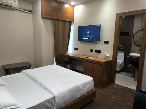 a bedroom with a bed and a desk with a television at BANMALI REGENCY in Jamshedpur