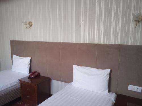 a hotel room with two beds and a phone on a table at ОРДА in Shymkent