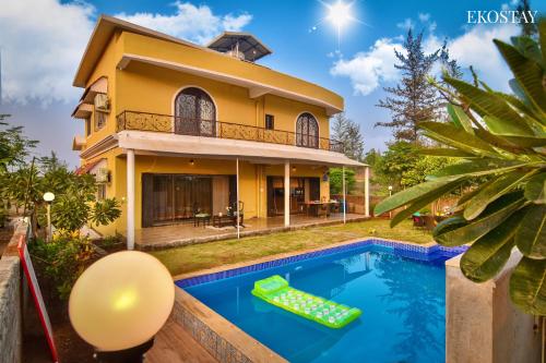 a villa with a swimming pool in front of a house at EKOSTAY- Nest Villa in Karjat