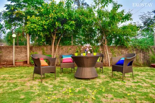 un grupo de sillas y una mesa en un patio en EKOSTAY- Nest Villa, en Karjat