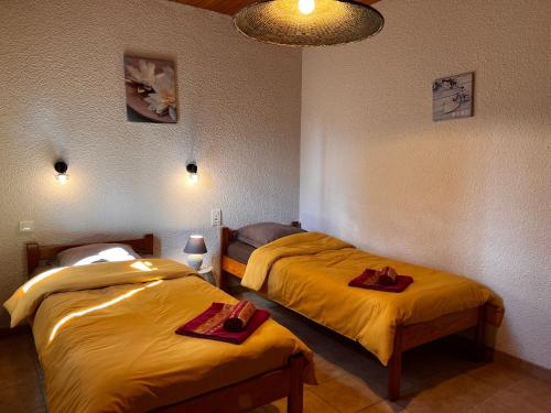 two beds in a room with yellow sheets at l'Espinet Vacances in Quillan