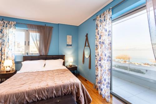 a bedroom with blue walls and a bed with a large window at Beachfront Artemida Retreat - Peony Seabreeze Gem in Artemida