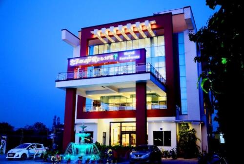 a large building with cars parked in front of it at Taraji Resort Hotel & Restaurant Ayodhya in Ayodhya