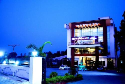 a building at night with cars parked in a parking lot at Taraji Resort Hotel & Restaurant Ayodhya in Ayodhya