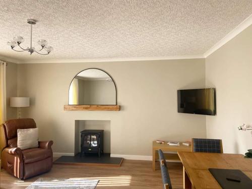 a living room with a chair and a fireplace at Cathwill - Cosy 4 Star Cottage - Cairngorm National Park in Newtonmore
