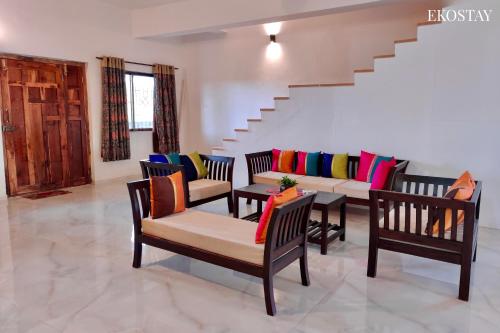 a living room with chairs and a table with colorful pillows at EKOSTAY- Nest Villa in Karjat