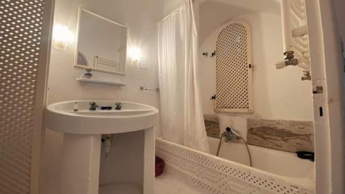 Dar Essarouel Hammamet في الحمامات: حمام أبيض مع حوض وحوض استحمام