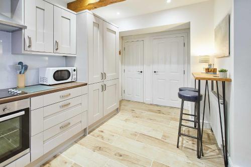 a kitchen with white cabinets and a microwave at Host & Stay - The Snug in Hunmanby