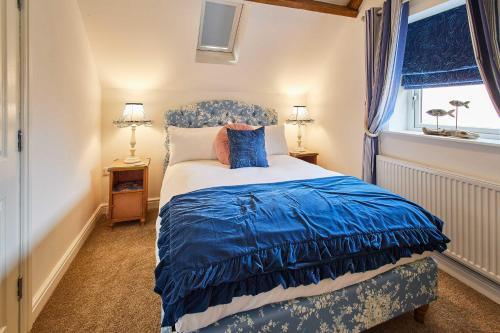 a bedroom with a blue and white bed with a window at Host & Stay - The Snug in Hunmanby