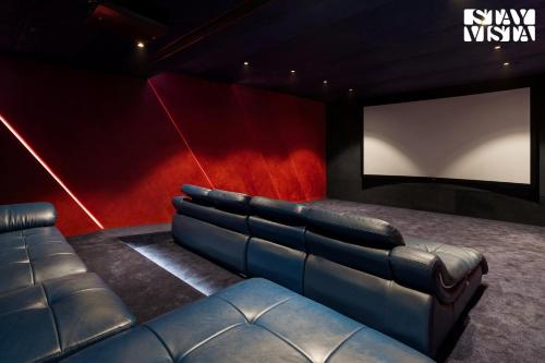 a cinema room with a leather couch and a screen at StayVista at AJ House with Pvt Pool & Projector Set-up in Hyderabad
