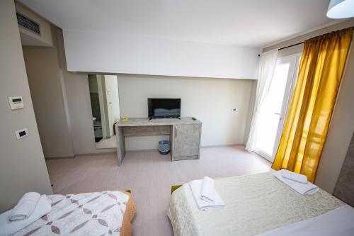 a room with two beds and a desk with a television at Hotel Miki in Durrës