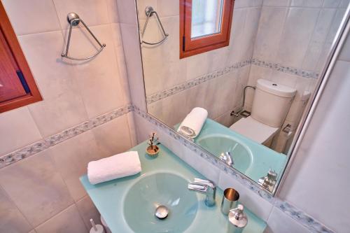 a bathroom with a sink and a mirror and a toilet at Utopia Beach Villa in Litherés