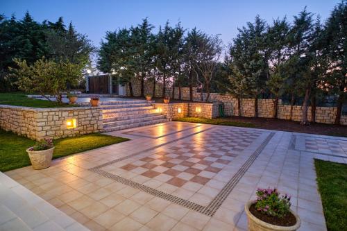 a backyard with a stone wall and a patio with lights at Utopia Beach Villa in Litherés