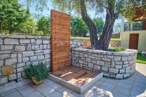 a wooden bench in front of a stone wall at Utopia Beach Villa in Litherés