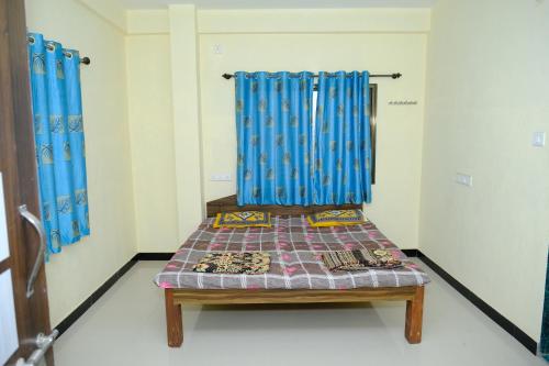 a room with a bench in a room with blue curtains at Aashray Guestroom 