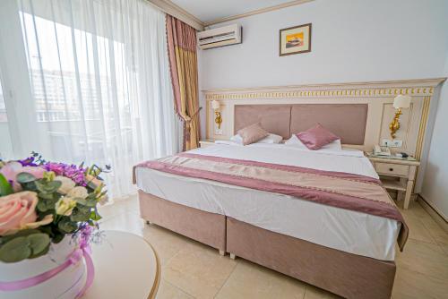a bedroom with a bed and a table with a vase of flowers at Hotel Sulina International in Mamaia