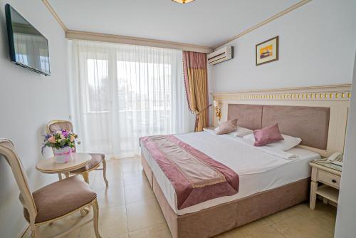 um quarto de hotel com uma cama e uma cadeira e uma janela em Hotel Sulina International em Mamaia