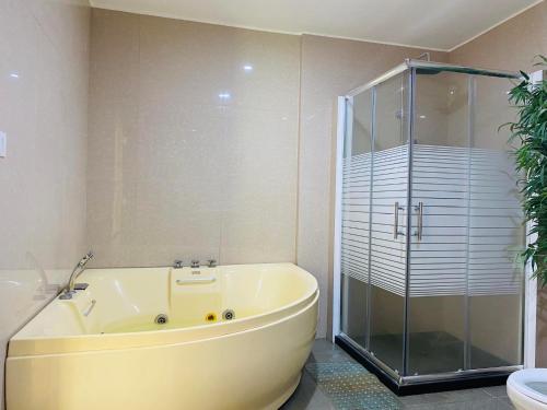 y baño con bañera grande y ducha acristalada. en Mariegold Villa Resort, en Suba