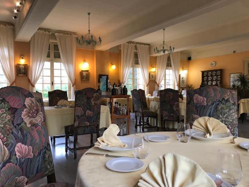 a dining room with a table with plates and chairs at Logis hôtel & Restaurant - Auberge de la Forêt in Hazebrouck