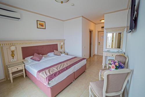 a bedroom with a large bed and a chair at Hotel Sulina International in Mamaia