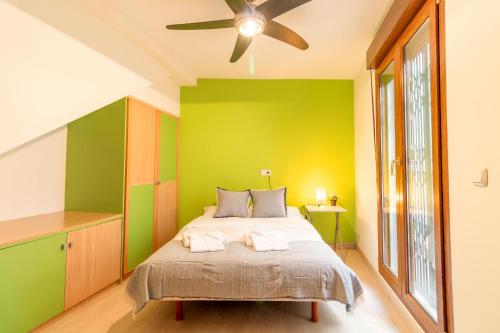 a green bedroom with a bed and a ceiling fan at RentitSpain - Almuñecar - Vistas Increíbles al mar en Apartamentos Lambda in Almuñécar