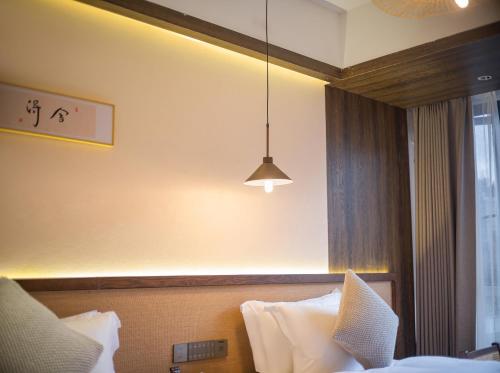 a hotel room with a bed and a pendant light at Lingxi Riverview Boutique Homestay - Phoenix Ancient Town in Fenghuang