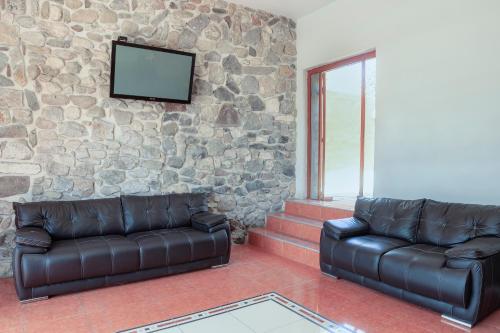 a living room with two leather couches and a stone wall at Capital O Del Valle, Tecamachalco in Tecamachalco