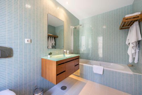 een badkamer met blauwe tegels, een wastafel en een bad bij Flamingo Apartment Olhão in Olhão