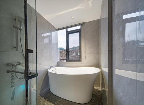 a bath tub in a bathroom with a window at Lingxi Riverview Boutique Homestay - Phoenix Ancient Town in Fenghuang