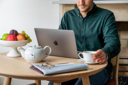 a man sitting at a table with a laptop computer at The Berkeley Square Hotel Bristol in Bristol