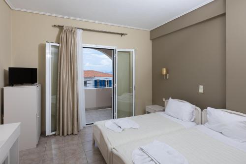 a hotel room with two beds and a balcony at Hotel Venetia in Perdika