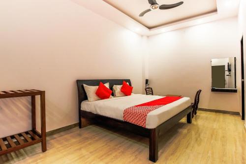 Schlafzimmer mit einem Bett mit roten Kissen und einem Spiegel in der Unterkunft Vaibhav Laxmi Paradise in Chinhat