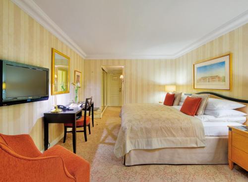 a hotel room with a bed and a desk and a television at InterContinental Wien by IHG in Vienna