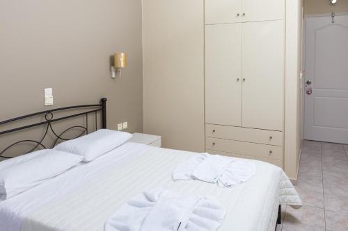 a bedroom with a white bed with towels on it at Hotel Venetia in Perdhika
