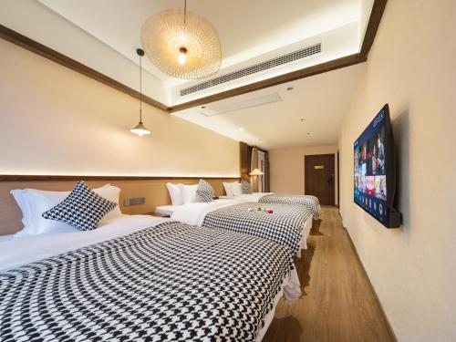 a hotel room with two beds and a flat screen tv at Lingxi Riverview Boutique Homestay - Phoenix Ancient Town in Fenghuang